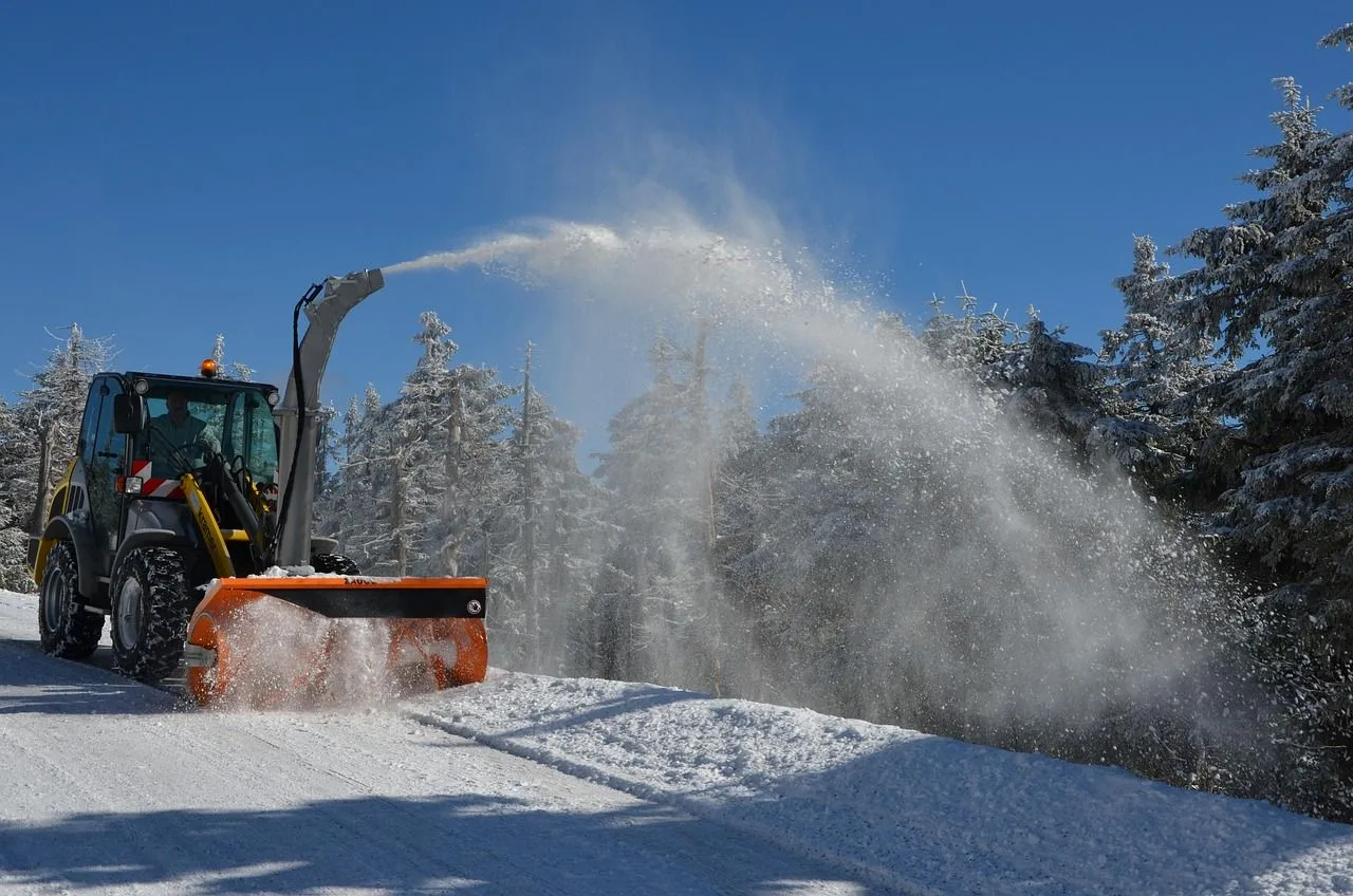 Traktor mit Schneefräse räumt eine verschneite Straße