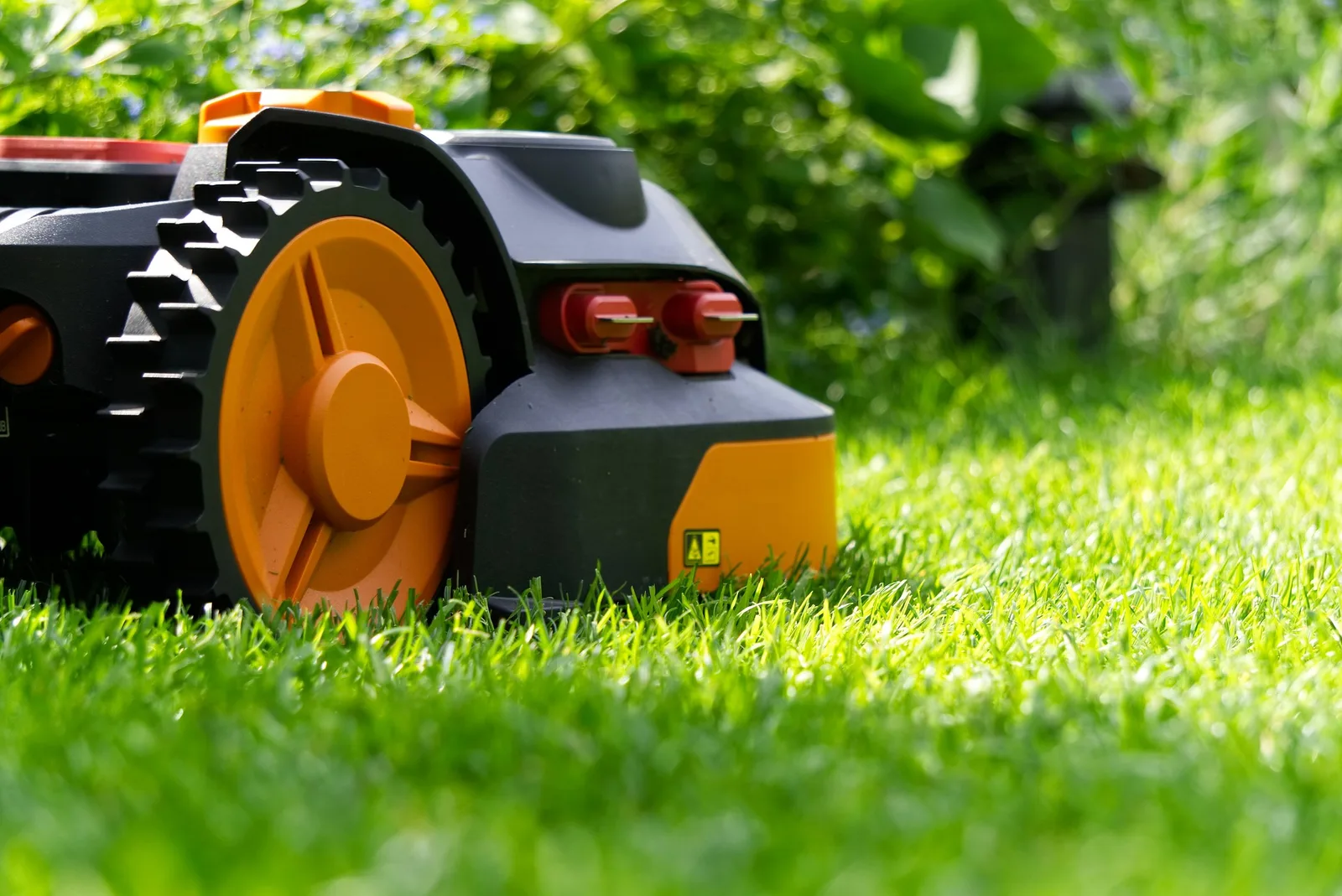 Mähroboter mit großen Antriebsrädern auf dem Rasen Mähroboter mit großen Antriebsrädern auf dem Rasen